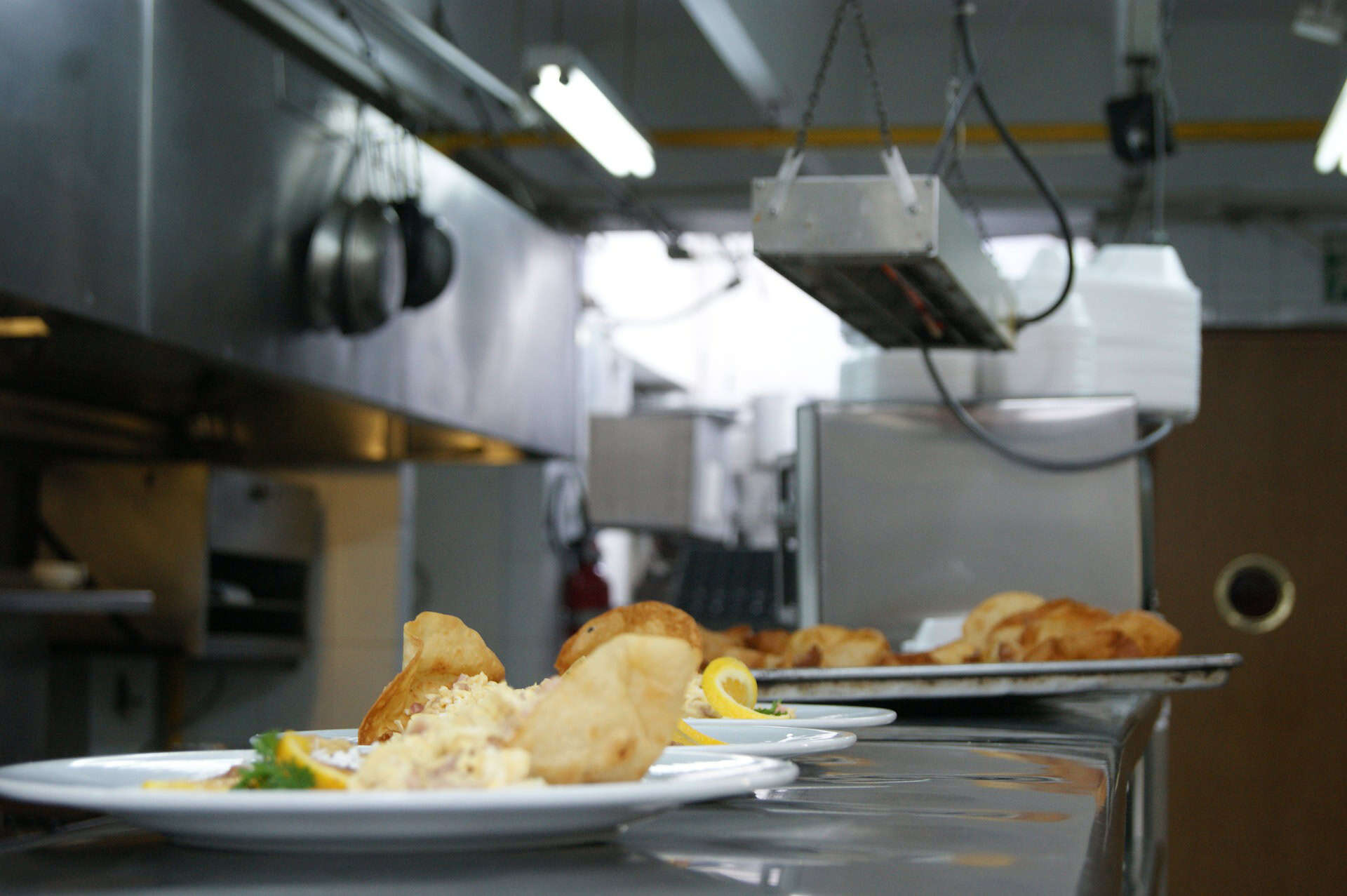 Prepared meals sitting on a counter under a food warmer in the kitchen of a restaurant.