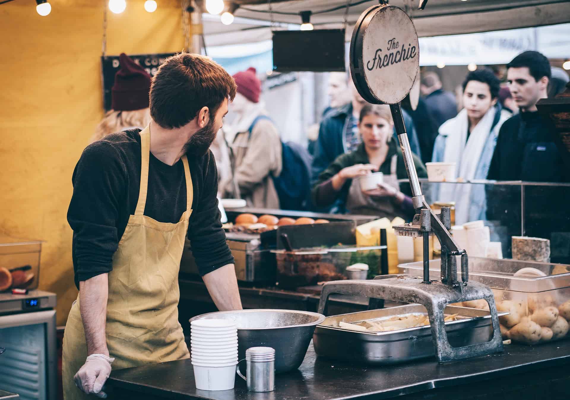 Chef stands behind the counter of his restaurant as customers wait for food.