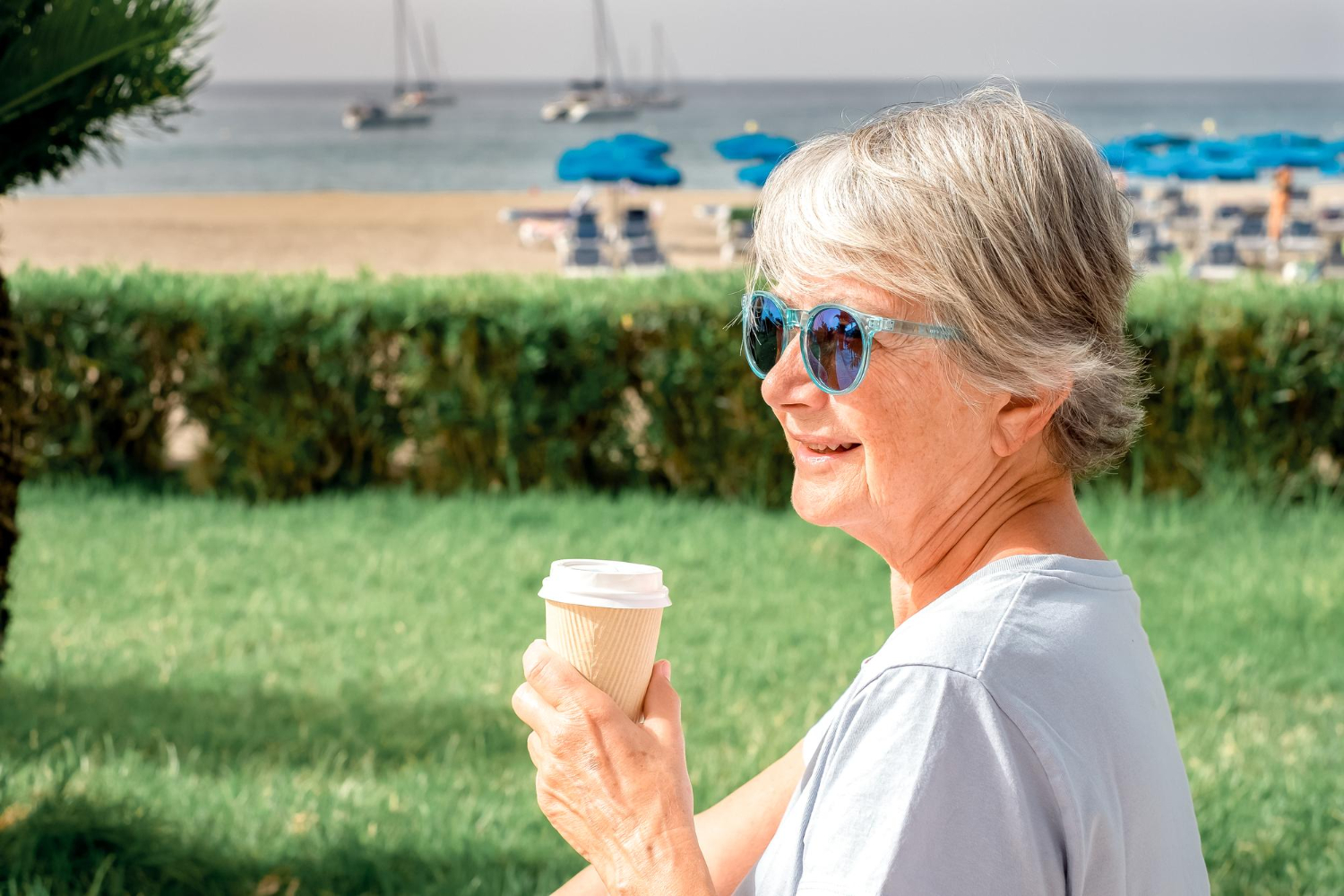 A senior woman enjoys a cup of coffee at a lakefront park on a gorgeous summer day.