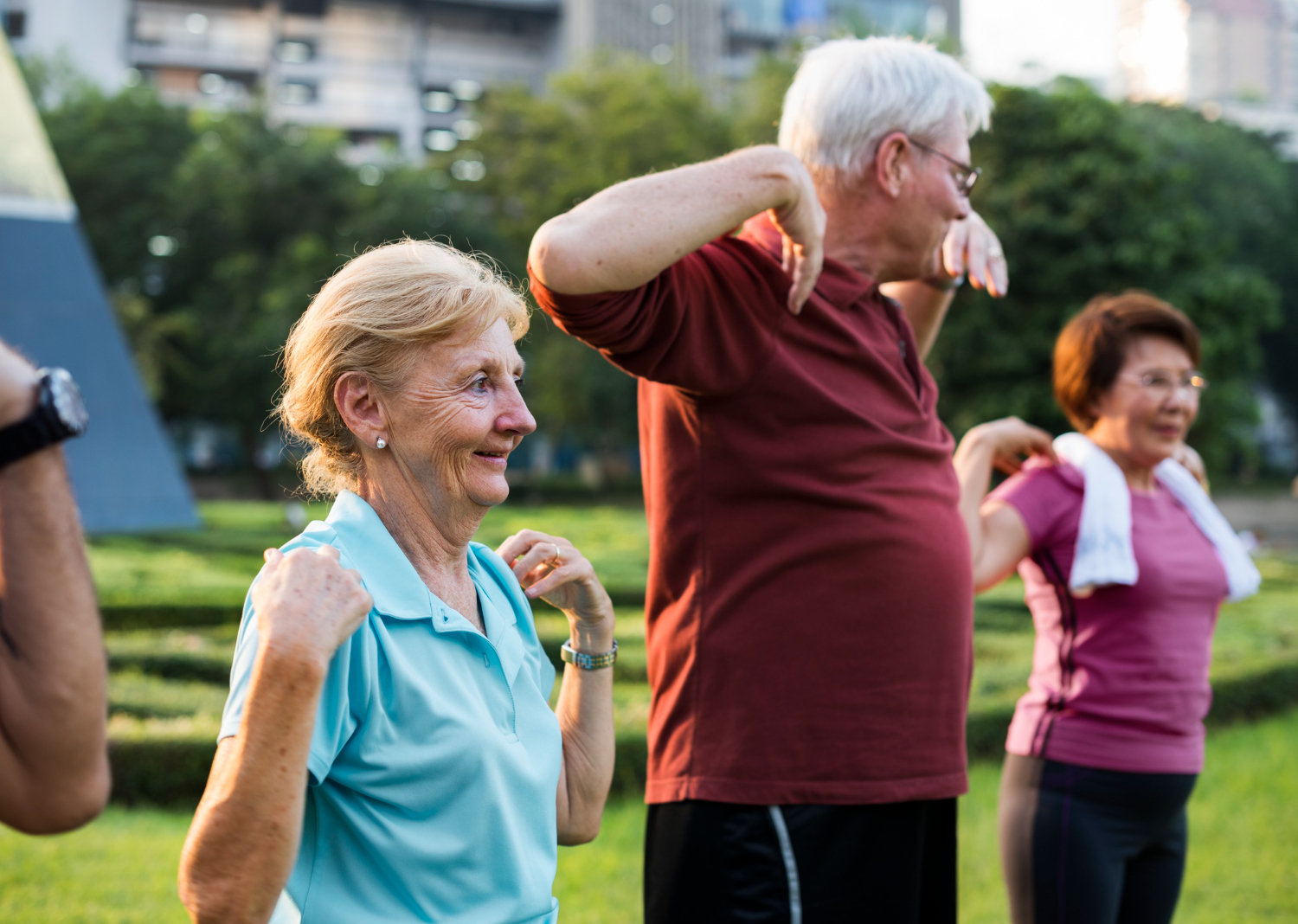 Three seniors workout in a soft exercise class in a park on a bright and sunny day.