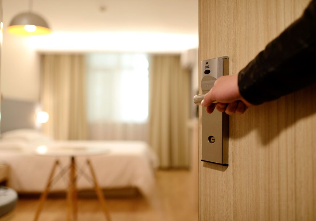 A man opening a hotel room door.