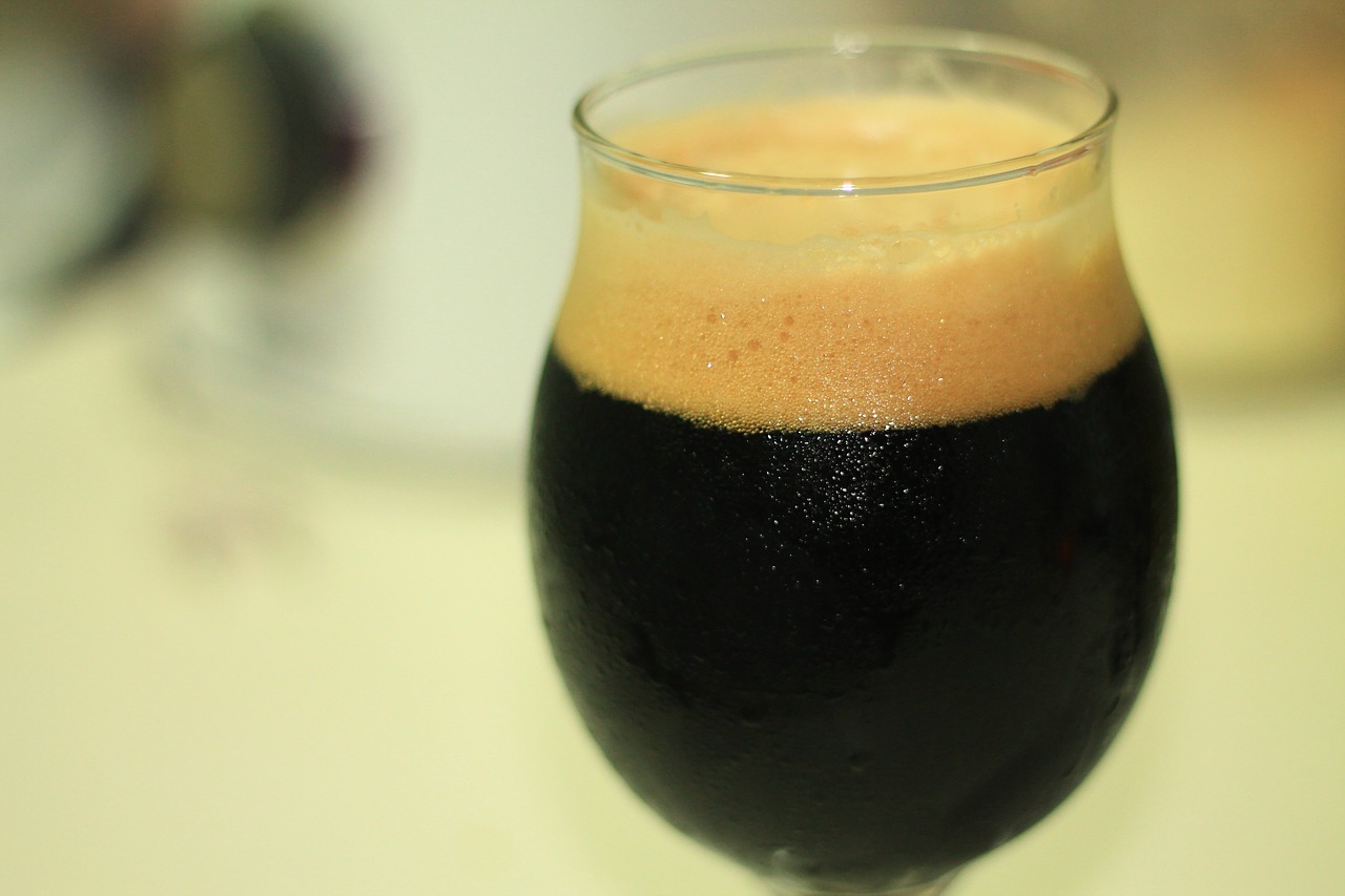 A half pint of dark milk stout beer with foamy head, a delicious sweet dessert beer brewed with lactose.