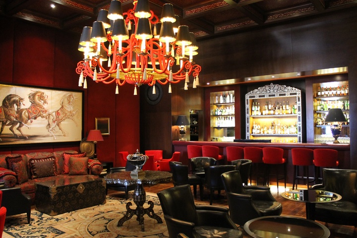 Deep red walls, a built-in bar, and leather chairs complement this Chinese style dining room and bar atmosphere. 