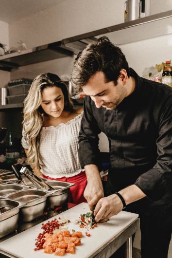 Two chefs in a restaurant kitchen chopping vegetables