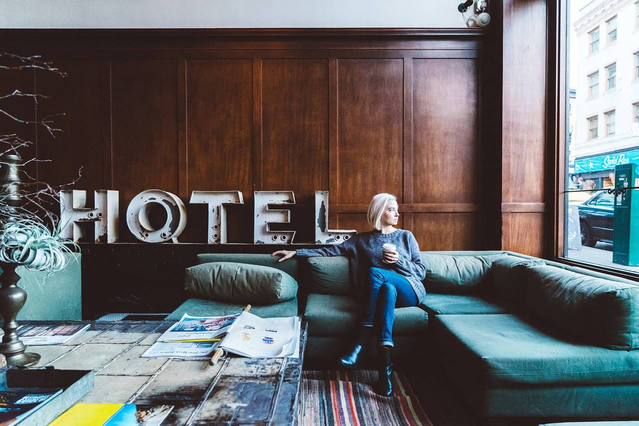 A woman sits in a boutique hotel lobby, enjoying a similar experience to an Airbnb rental; both offer memorable experiences in unique spaces. 