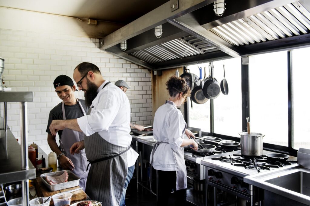 A group of employees preparing food in a restaurant kitchen help their business succeed by using resources offered by legal and government agencies.