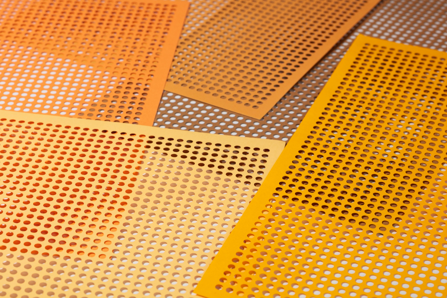 Yellow and orange nonslip bathmats lay on a white floor. The mats are made of nonslip silicone and have holes throughout to allow for water drainage.