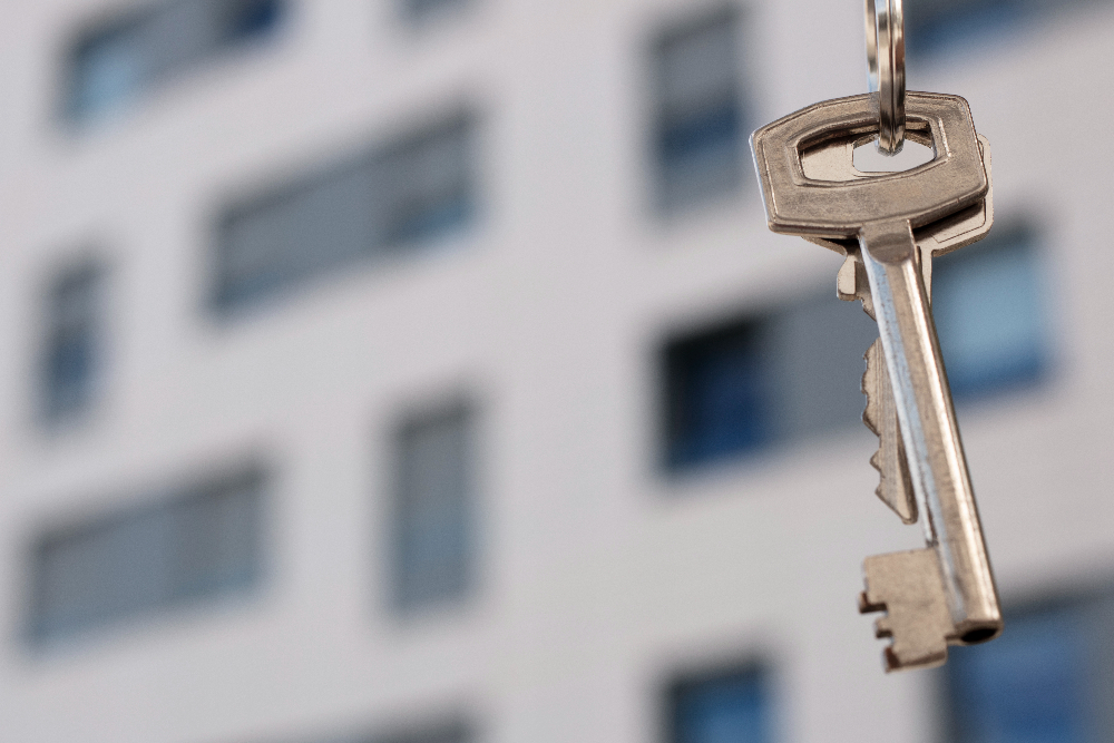 A close-up of keys in front of an apartment building. Landlords need a strong building key policy. 